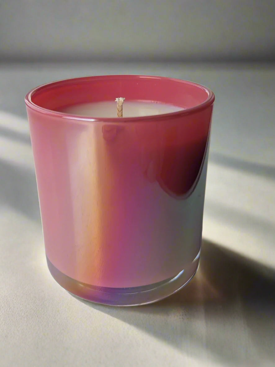 Candle in a pink glass container on a white surface